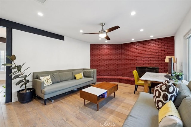 living room with a brick fireplace, light hardwood / wood-style floors, and brick wall