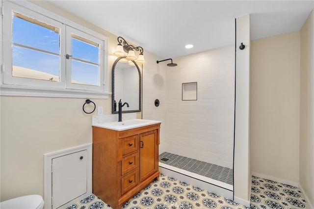 bathroom featuring tile patterned flooring, vanity, a tile shower, and toilet