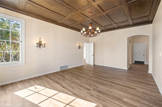 unfurnished room with hardwood / wood-style flooring, ornamental molding, coffered ceiling, and an inviting chandelier