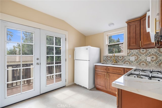 kitchen with vaulted ceiling, sink, backsplash, white appliances, and french doors