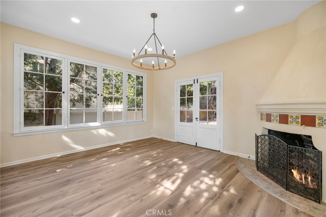 unfurnished dining area featuring a high end fireplace, a chandelier, and hardwood / wood-style floors