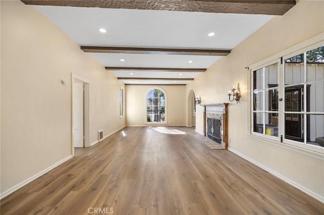 unfurnished living room featuring hardwood / wood-style floors and beam ceiling