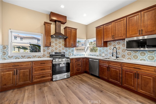 kitchen with premium range hood, sink, light hardwood / wood-style flooring, stainless steel appliances, and backsplash