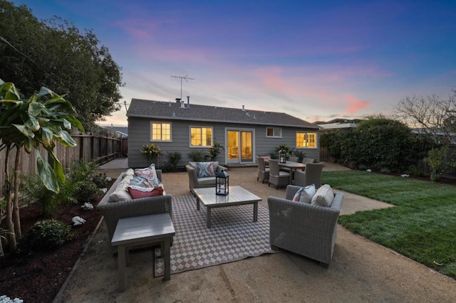 back house at dusk featuring a patio, an outdoor hangout area, and a yard