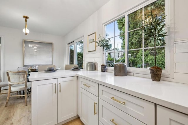 kitchen with light hardwood / wood-style flooring, pendant lighting, white cabinets, and kitchen peninsula