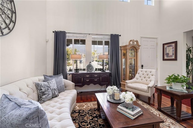 living room featuring a towering ceiling, plenty of natural light, and hardwood / wood-style floors