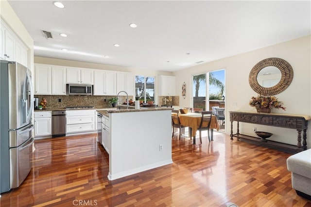 kitchen featuring white cabinetry, stainless steel appliances, and dark stone counters