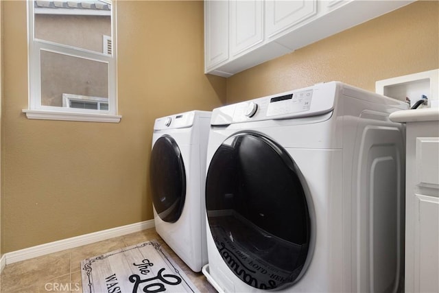 laundry area featuring light tile patterned floors, washer and clothes dryer, and cabinets