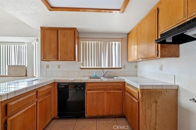 kitchen with sink, black dishwasher, tile counters, light tile patterned floors, and a textured ceiling