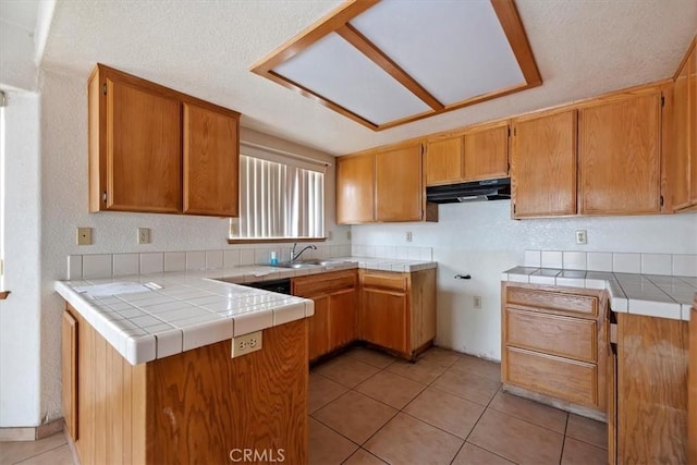 kitchen with tile countertops, kitchen peninsula, sink, and light tile patterned floors