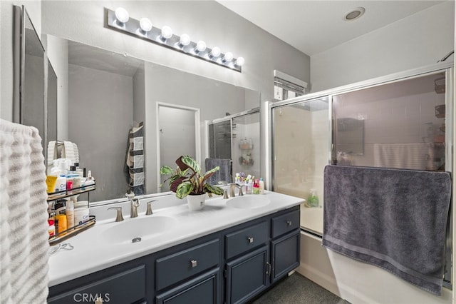 bathroom with double vanity, bath / shower combo with glass door, and a sink