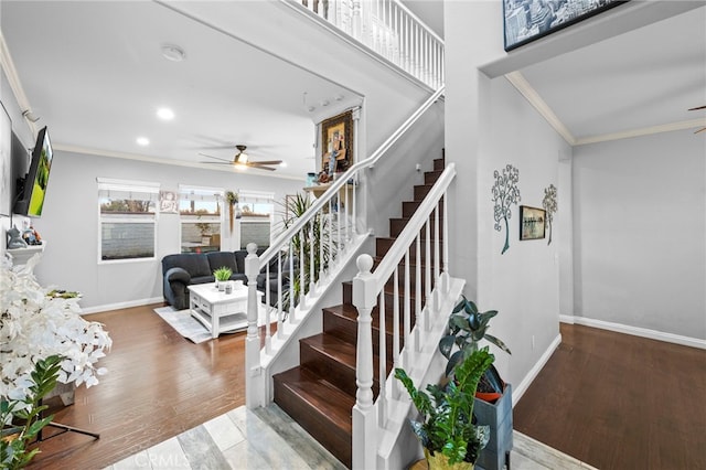 stairs with a ceiling fan, crown molding, baseboards, and wood finished floors