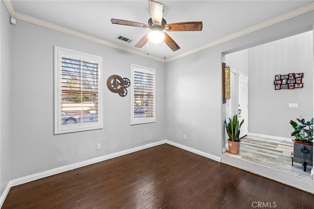 spare room featuring crown molding, baseboards, and wood finished floors