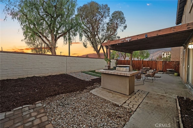 yard at dusk with a fire pit, a patio, a fenced backyard, and a pergola