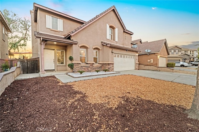 view of front facade with driveway, stone siding, an attached garage, and stucco siding