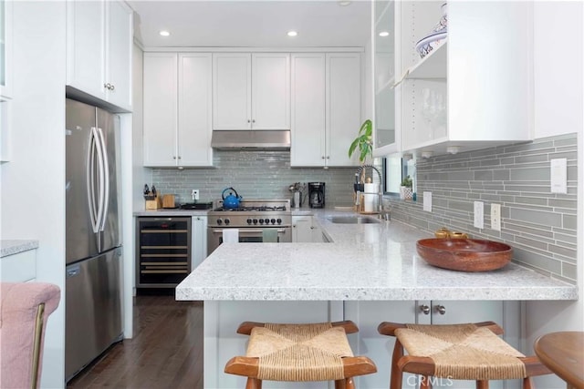 kitchen with stainless steel appliances, beverage cooler, sink, and a breakfast bar area