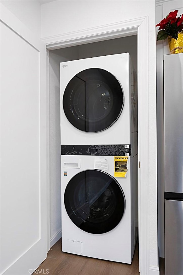 laundry area with stacked washing maching and dryer and dark hardwood / wood-style floors