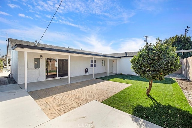 rear view of property featuring a patio and a lawn