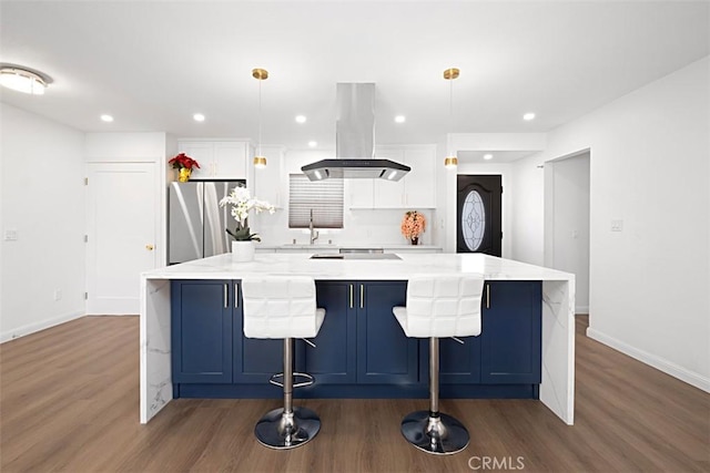 kitchen featuring stainless steel fridge, white cabinetry, island range hood, and decorative light fixtures