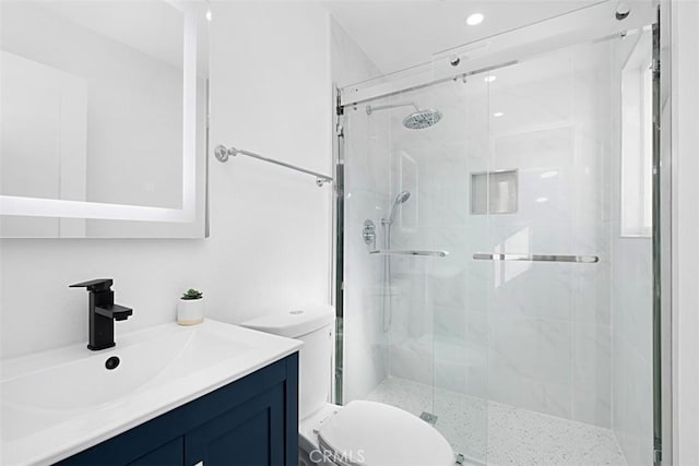 bathroom with vanity, a shower with shower door, and toilet