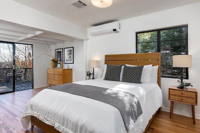 bedroom featuring hardwood / wood-style floors, a wall mounted air conditioner, access to exterior, and multiple windows