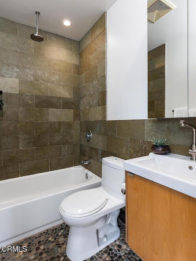 full bathroom featuring toilet, tiled shower / bath, tile walls, vanity, and decorative backsplash