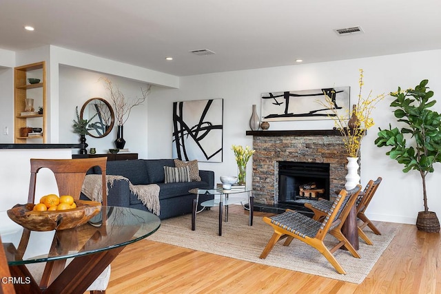 living room with a stone fireplace and wood-type flooring