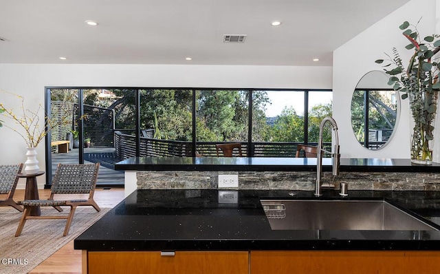 kitchen with sink, dark stone countertops, and light wood-type flooring