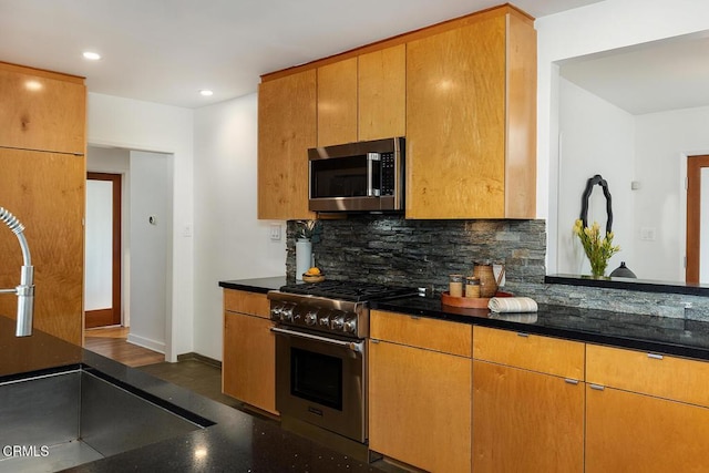 kitchen with stainless steel appliances, sink, dark stone countertops, and backsplash