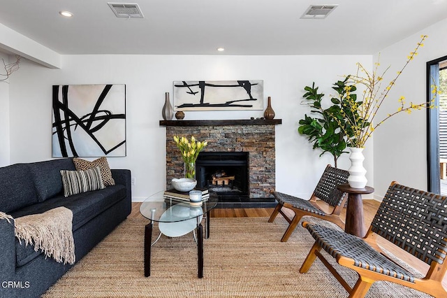 living room with wood-type flooring and a stone fireplace