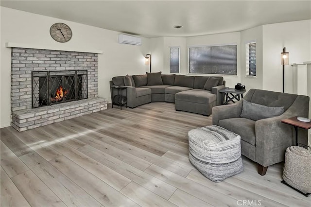 living room with a brick fireplace, a wall mounted air conditioner, and light wood-type flooring