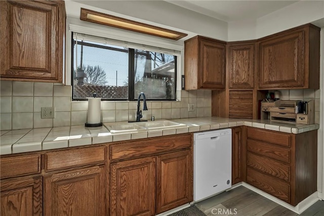 kitchen featuring sink, dark wood-type flooring, white dishwasher, tasteful backsplash, and tile countertops