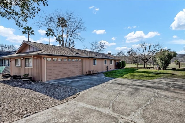 view of home's exterior featuring a garage, roof with shingles, a yard, and driveway