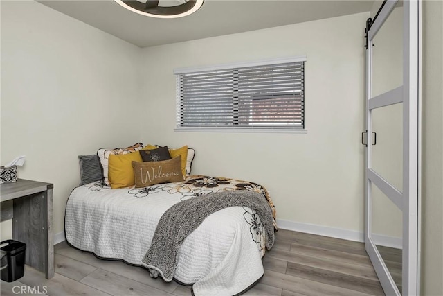 bedroom with wood-type flooring and a barn door