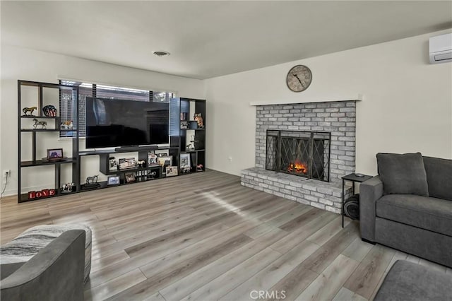 living room with hardwood / wood-style flooring, a fireplace, and an AC wall unit