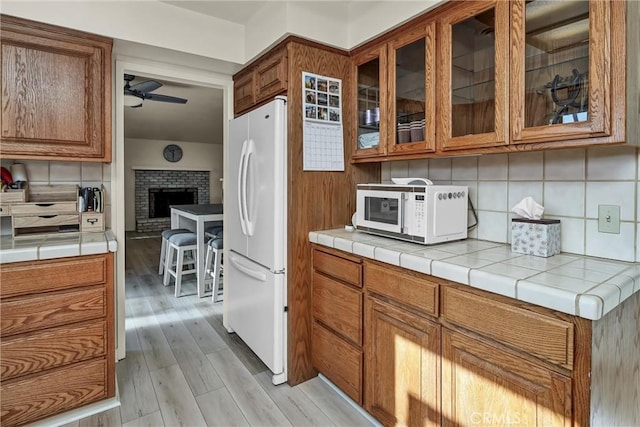 kitchen with backsplash, white appliances, and tile countertops