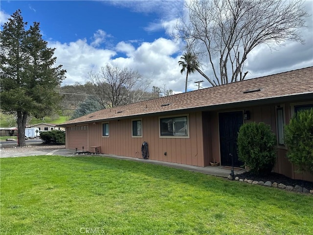 rear view of house featuring a yard and roof with shingles