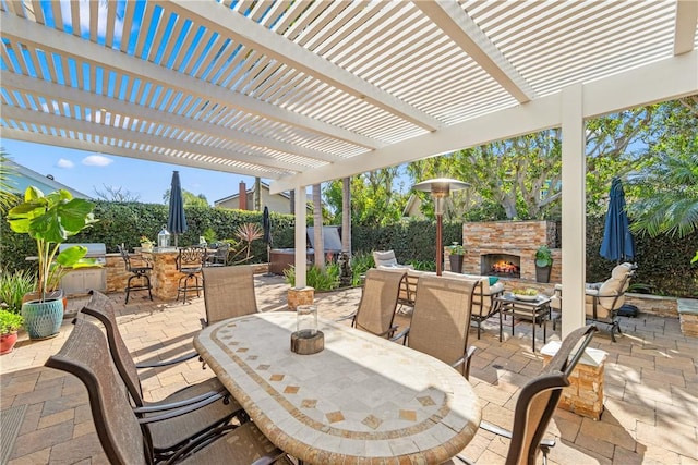 view of patio with fence, an outdoor stone fireplace, area for grilling, and outdoor dining space