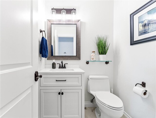 half bathroom with toilet, marble finish floor, baseboards, and vanity