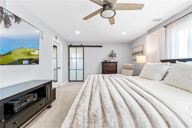 bedroom with a barn door, light colored carpet, visible vents, baseboards, and a ceiling fan