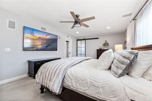 bedroom with a barn door, visible vents, baseboards, and light colored carpet