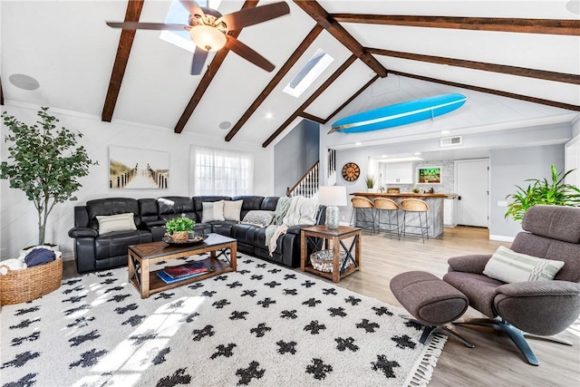 living room featuring beam ceiling, stairway, visible vents, and light wood-style floors