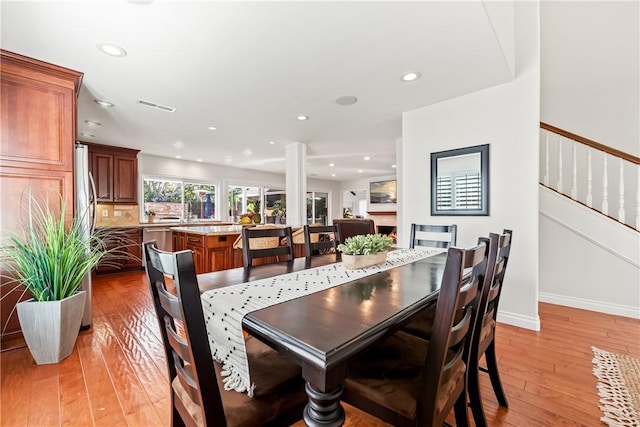 dining area featuring recessed lighting, visible vents, stairway, light wood finished floors, and decorative columns