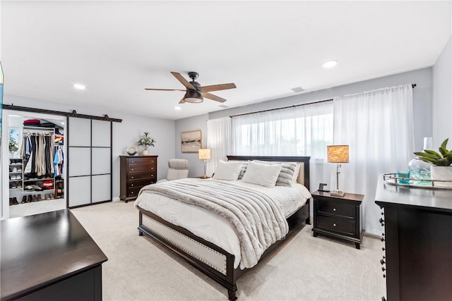 bedroom with recessed lighting, a spacious closet, a barn door, light carpet, and ceiling fan