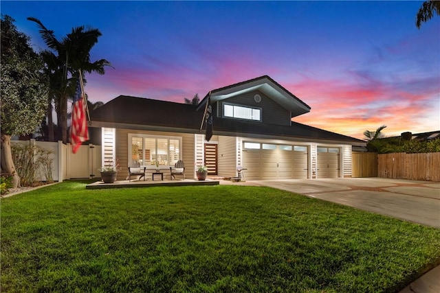 view of front of house with fence, concrete driveway, and a yard