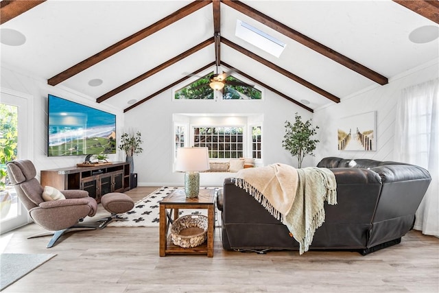 living area with high vaulted ceiling, beamed ceiling, a skylight, and wood finished floors