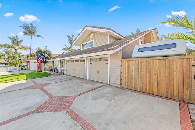 view of front of home featuring concrete driveway and fence