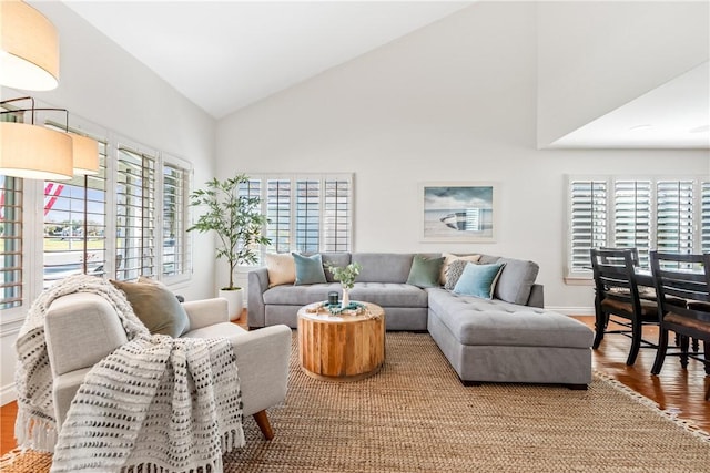 living room featuring baseboards, high vaulted ceiling, and wood finished floors