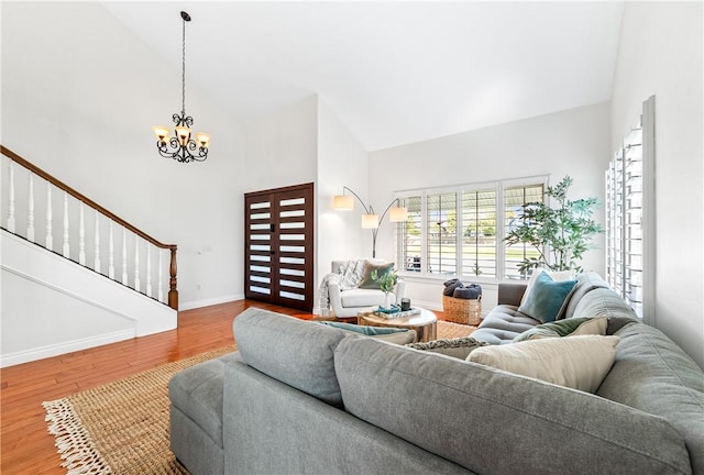 living room with baseboards, a chandelier, wood finished floors, stairs, and high vaulted ceiling