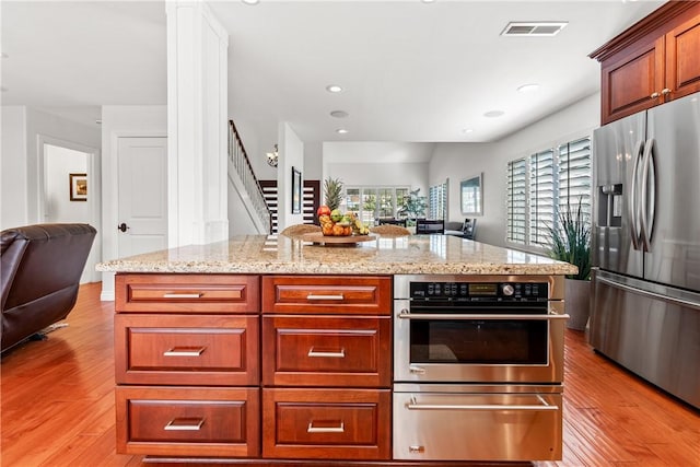 kitchen featuring appliances with stainless steel finishes, light wood-type flooring, open floor plan, and a warming drawer